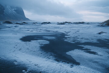 A frozen Icelandic landscape with a dark icy lake contrasting against the surrounding snow-covered...