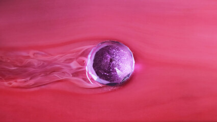 Floating christmas ball. Wet paint. Defocused purple red color glitter glow globe smooth wave ink texture on abstract art background.