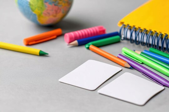 Colorful School Supplies on Gray Background Featuring Globe, Notepad, and Blank Cards