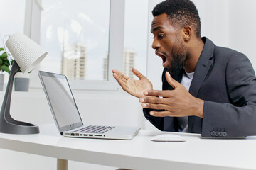 Businessman shocked at unexpected news on laptop screen while working at office desk