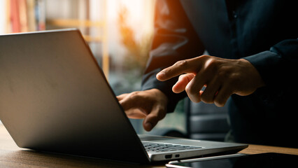 Closeup of businessman hand typing on laptop computer at office. A person is typing on a laptop with a finger pointing to the screen. Business man working on computer device