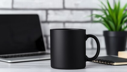 A stylish black mug on a workspace desk, accented by a laptop, potted plant, and notepad for a productive vibe.