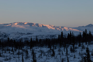 Sun shininig on top of snowy mountaintop in interior Alaska