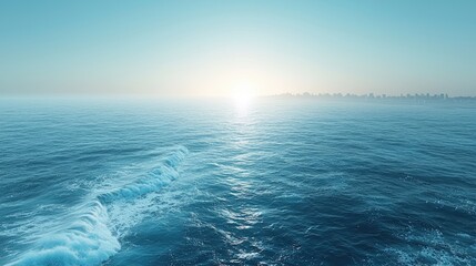 Obraz premium Serene sunrise over a calm ocean with distant city skyline and gentle waves in foreground