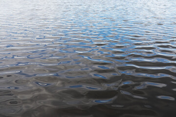 Calm Blue Rippled Water Surface with Gentle Waves Reflecting Sky and Clouds