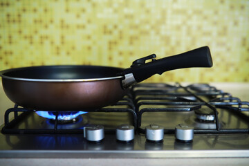 Frying Pan on Gas Stove with Blue Flame in Modern Kitchen