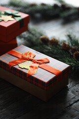 Festive Plaid Gift Box with Red Ribbon on Wooden Table Surrounded by Pine Garland