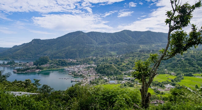 Scenic Landscape View of Lake Toba Surrounded by Lush Green Hills and a Vibrant Blue Sky Near Parapat