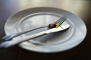Vitamins and Supplements on Fork and Knife on White Plate - Health and Nutrition Concept