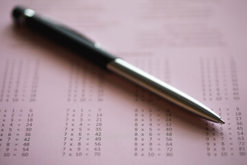 Close-up of Pen on Mathematical Worksheet with Multiplication Tables