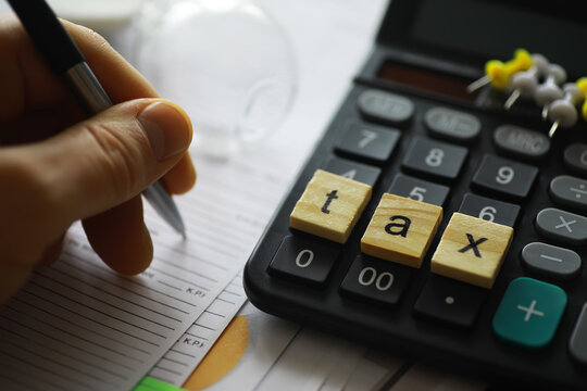 Hand Writing on Tax Forms with Calculator in Background