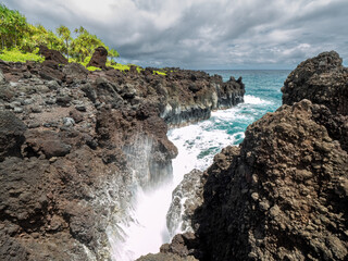 Obraz premium Get with me to the Waianapanapa Park and the rough lava cliffs which make the water splash up