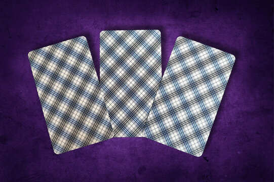 Trois cartes de tarot pos&eacute;es de dos, cr&eacute;ant une atmosph&egrave;re de myst&egrave;re et d&rsquo;inconnu. Carte sur fond violet textur&eacute;