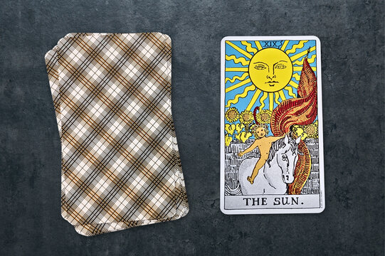 La carte repr&eacute;sent&eacute;e est "Le Soleil" du jeu de tarot Rider-Waite. Elle symbolise la joie, la clart&eacute; et le succ&egrave;s, avec un soleil rayonnant illuminant un enfant sur un cheval blanc. Fond gris textur&eacute;