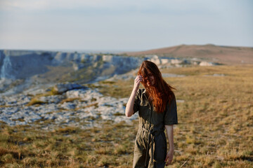 Woman with red hair standing in field with mountain in background on adventure travel trip beauty in nature concept