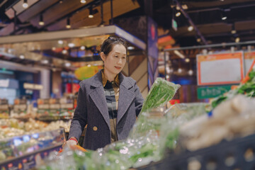 Woman Choosing Fresh Vegetables in Modern Supermarket