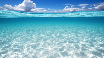 Obraz premium Clear turquoise shallow water, sunlight reflecting on the surface, fluffy white clouds in a brilliant blue sky above, underwater view, serene