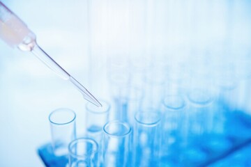 A close-up of a laboratory pipette dropping liquid into test tubes, symbolizing scientific research, medical testing, and pharmaceutical development.  .
