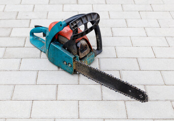 Fototapeta premium A dirty chainsaw laying on the ground