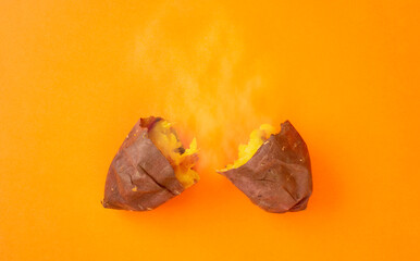 Baked sweet potato on the orange background and steam. オレンジ色背景上の焼き芋（サツマイモ）と湯気。
