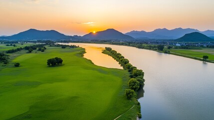 Fototapeta premium Aerial View of Green Grassland and River with Mountains at Sunset