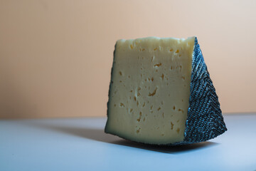 Unique triangular cheese block displayed against a smooth, neutral background in a modern setting