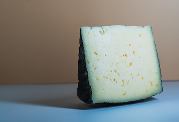 Delicious cheese block featuring a black rind and creamy yellow interior with small flecks, perfect...