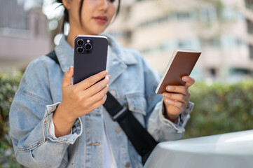 A close-up of a woman checks her passport, flight details on her phone before getting into a taxi.