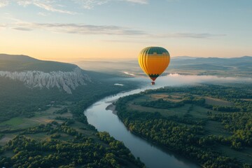 Fototapeta premium Hot air balloon floats above serene river landscape at dawn with mountains in the background