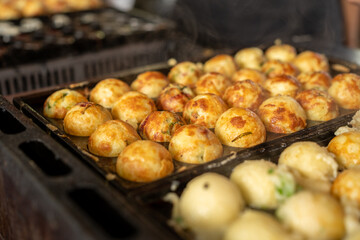 Golden Takoyaki Balls Cooking On A Traditional Griddle in a Food Market