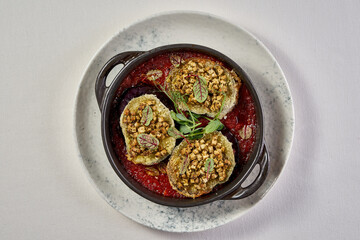 A vibrant and appetizing plate of baked eggplant, topped with a flavorful sauce and fresh herbs.