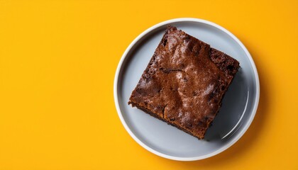 Chocolate cake on white plate on a yellow background