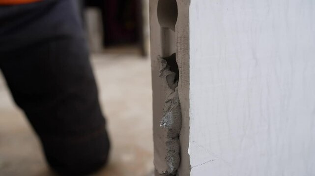 Construction worker spreading mortar on a precast concrete wall panel during building construction