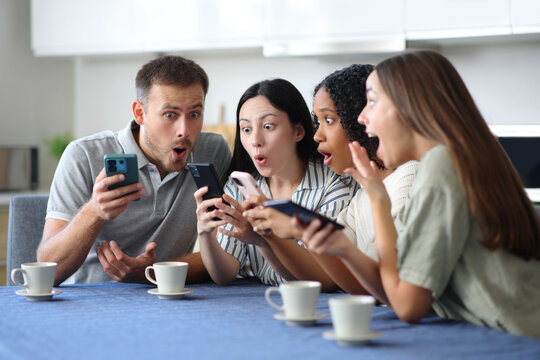 Amazed interracial group of friends checking phones