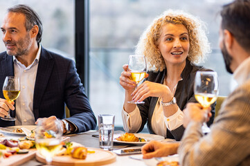 Portrait of businesswoman sitting with coworkers in restaurant during business lunch.
