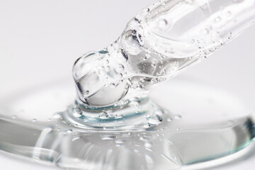 Dropper with hyaluronic acid macro. Transparent cosmetic texture with bubbles on a light gray background, front view.