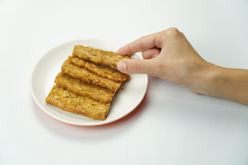 Hand Reaching for Tempeh on Plate isolated on white background