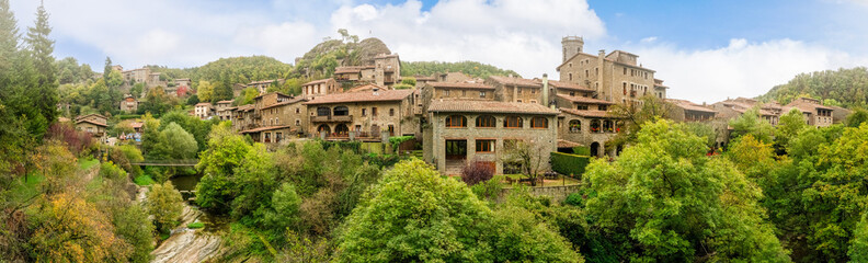 Fototapeta premium The enchanting village of Rupit i Pruit, near Piscines Municipals, Spain, boasts rustic stone houses nestled amidst lush greenery, offering a picturesque Catalonian landscape.