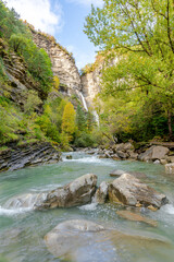 A breathtaking waterfall in Sobrarbe, cascading down layered limestone cliffs into a turquoise...