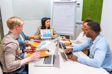 Business team analyzing graphs and charts during meeting in coworking office