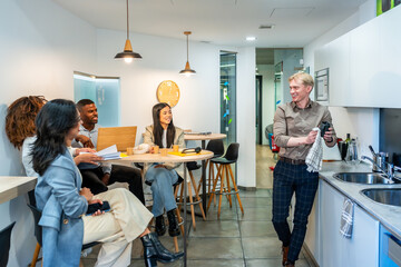 Coworkers chatting and having coffee break in coworking office kitchen