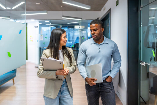 Business colleagues walking and talking in modern office hallway