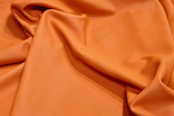 Natural piece of leather in orange color. Textured background