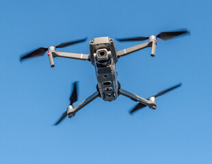 Drone landing with blades stopped midair blue sky behind
