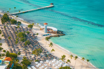 Bayahibe beach with palms,parasol, lighthouse,pier and turquoise sea in the Dominican Republic