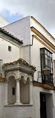 Jerez de la Frontera; white historic building with a small balcony supported by columns and arches, and a black wrought-iron lantern beside a wooden window frame.