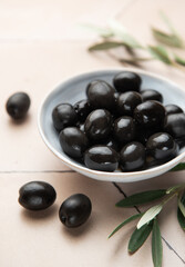 Black olives served in ceramic bowl on hexagonal beige tiles, decorated with olive tree branch