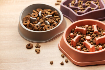 Slow feeder dog bowls with various dry food on wooden table