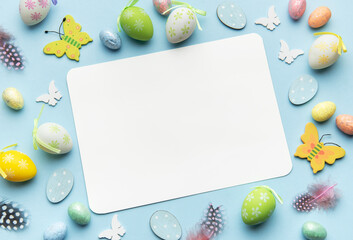 Easter decoration forming frame around blank card on blue background