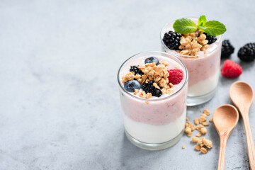Yogurt parfait with berries and granola on a grey concrete table background, copy space for design or text. Clean eating, dieting concept